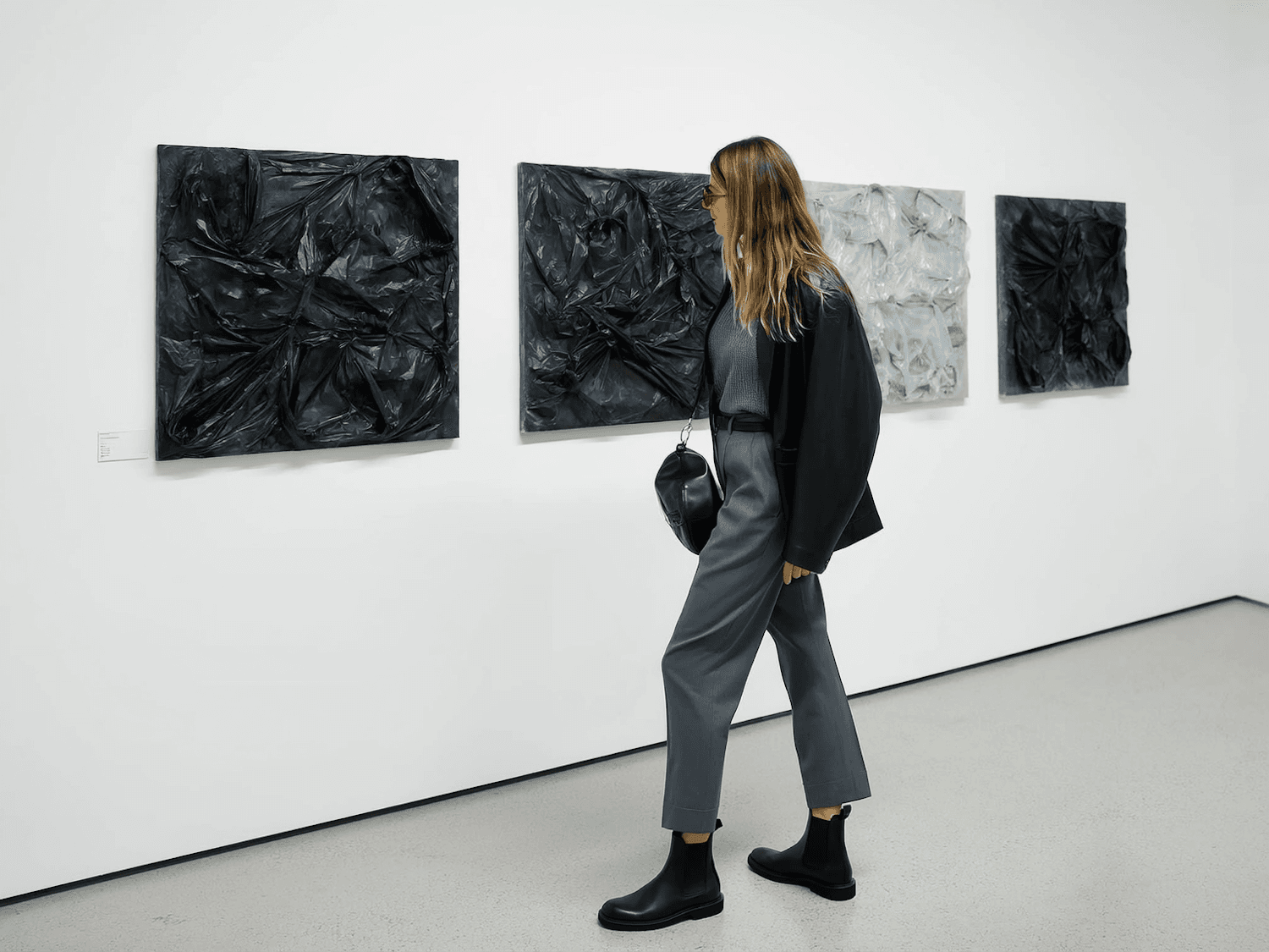 A visitor considering a textured work hung on a white gallery wall